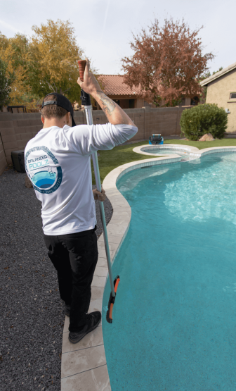 Pool service technician from Balanced Poolz in Chandler Az skimming debris from a pool
